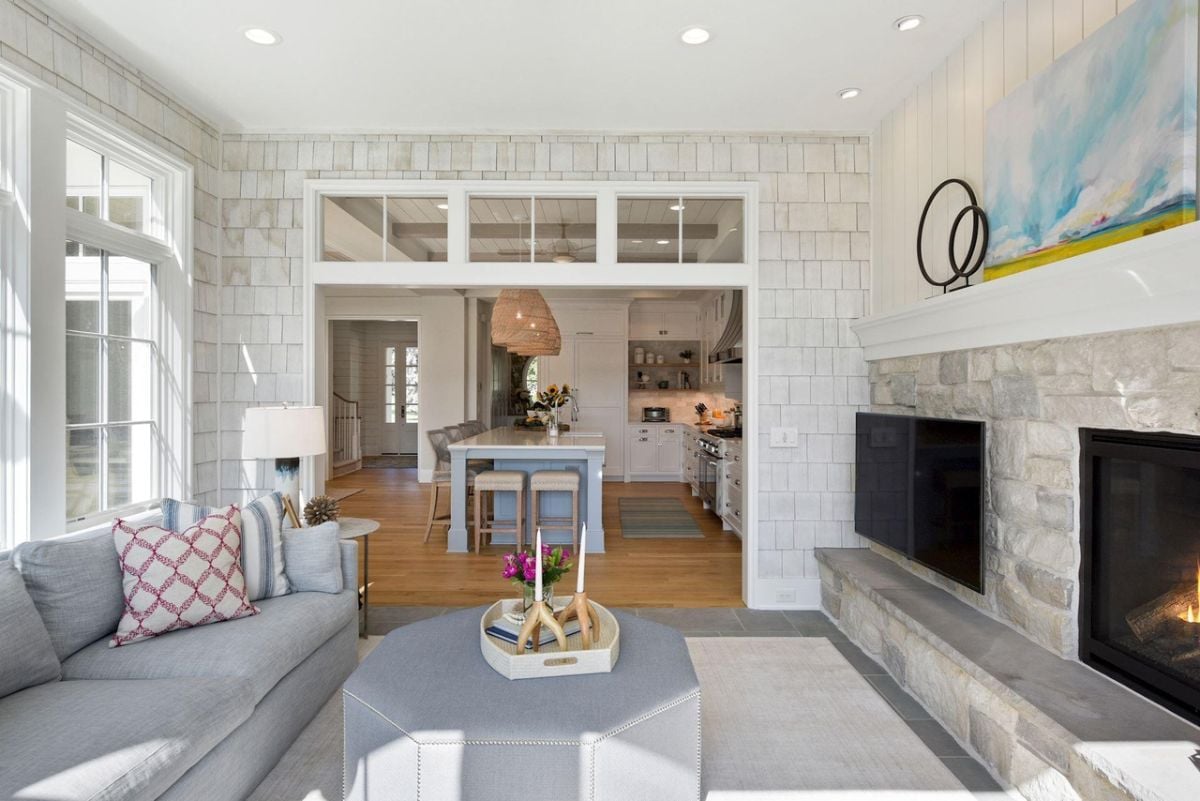 Living room with couches, a TV, glass windows and a fireplace.