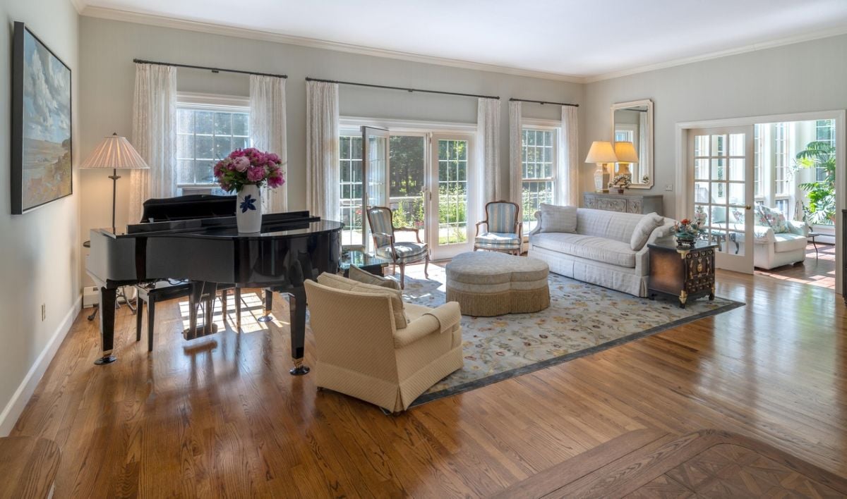 Living room with couches, piano, glass door, glass walls, and a rug.