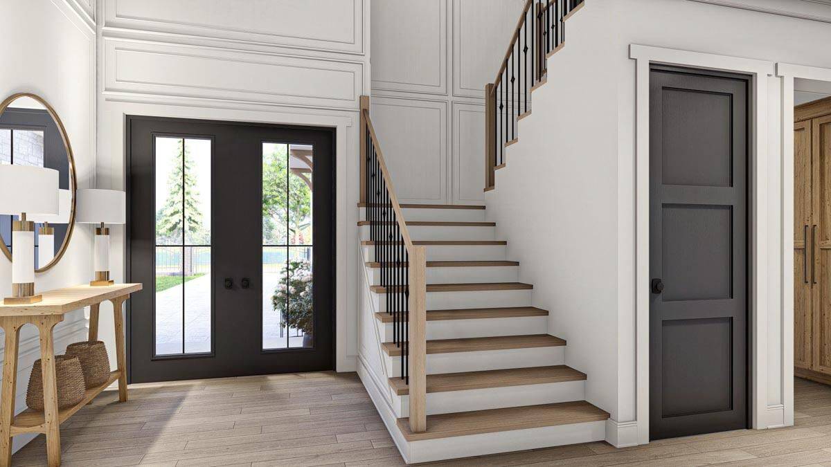 Foyer with a French front door, a staircase, and a wooden console table topped with a round mirror.