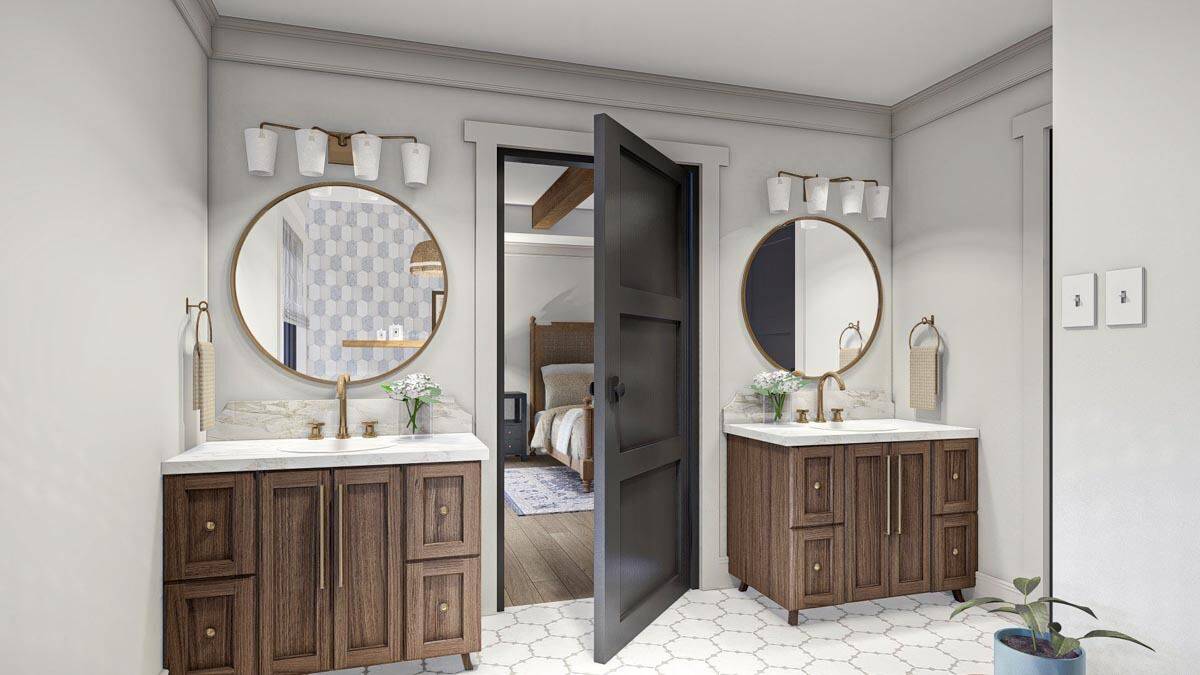 His and her vanities with wooden cabinets, marble countertops, and round mirrors.