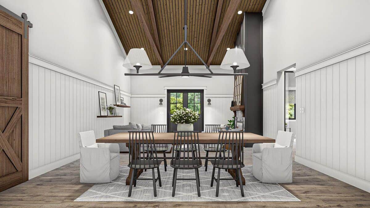 Dining room with a wrought iron chandelier and an 8-seater dining set over a patterned area rug.