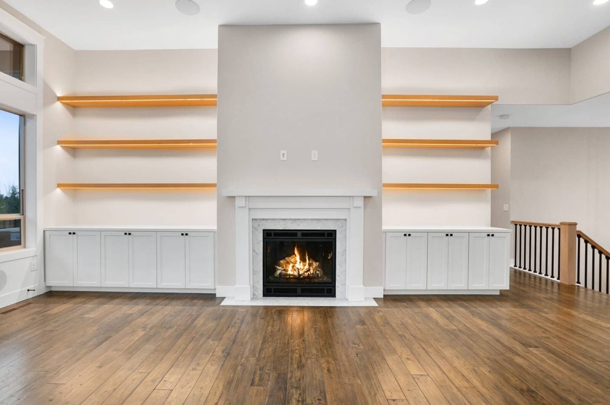 Living room with a fireplace, wooden floors, and custom lights.