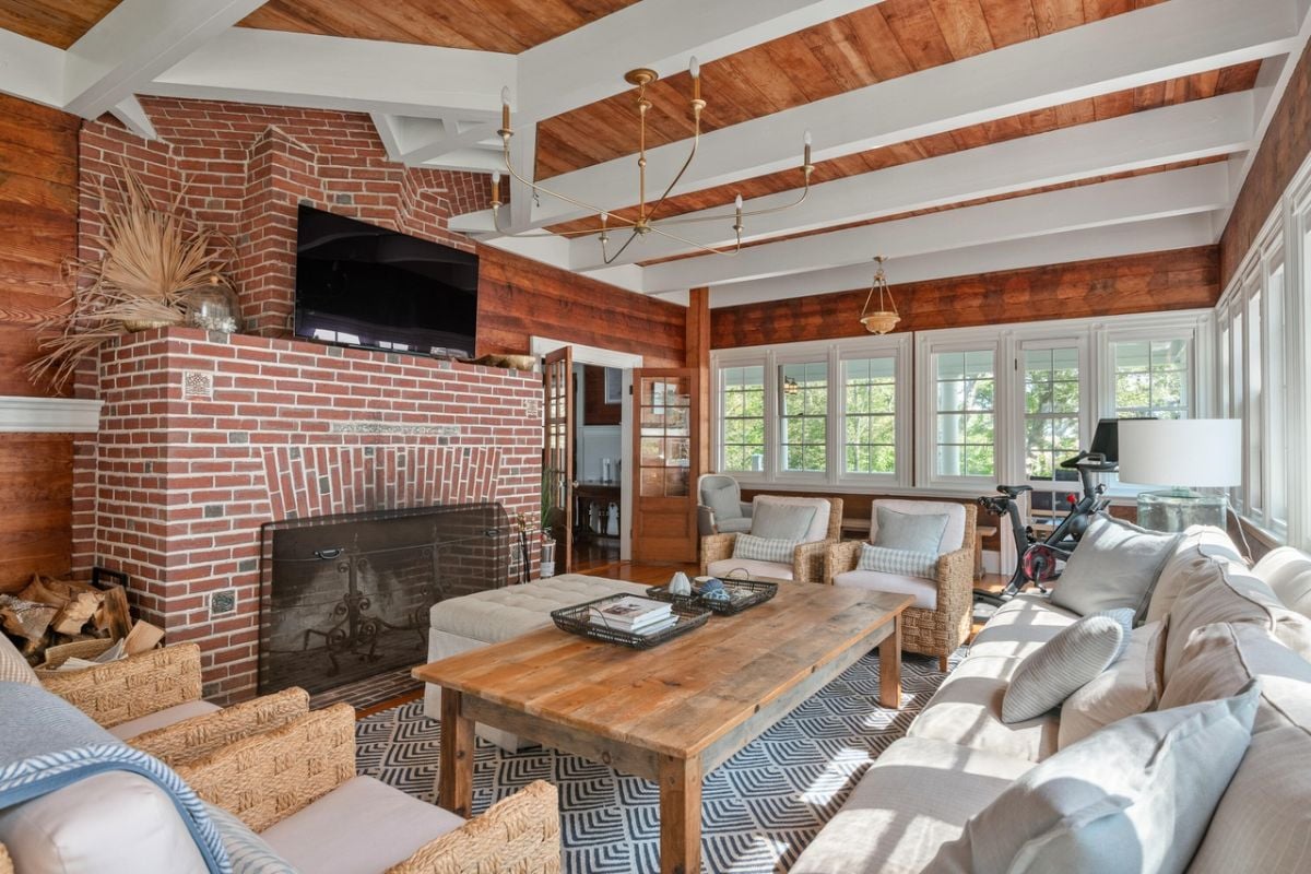 Living room with couches, rug, chandelier, TV and glass windows.