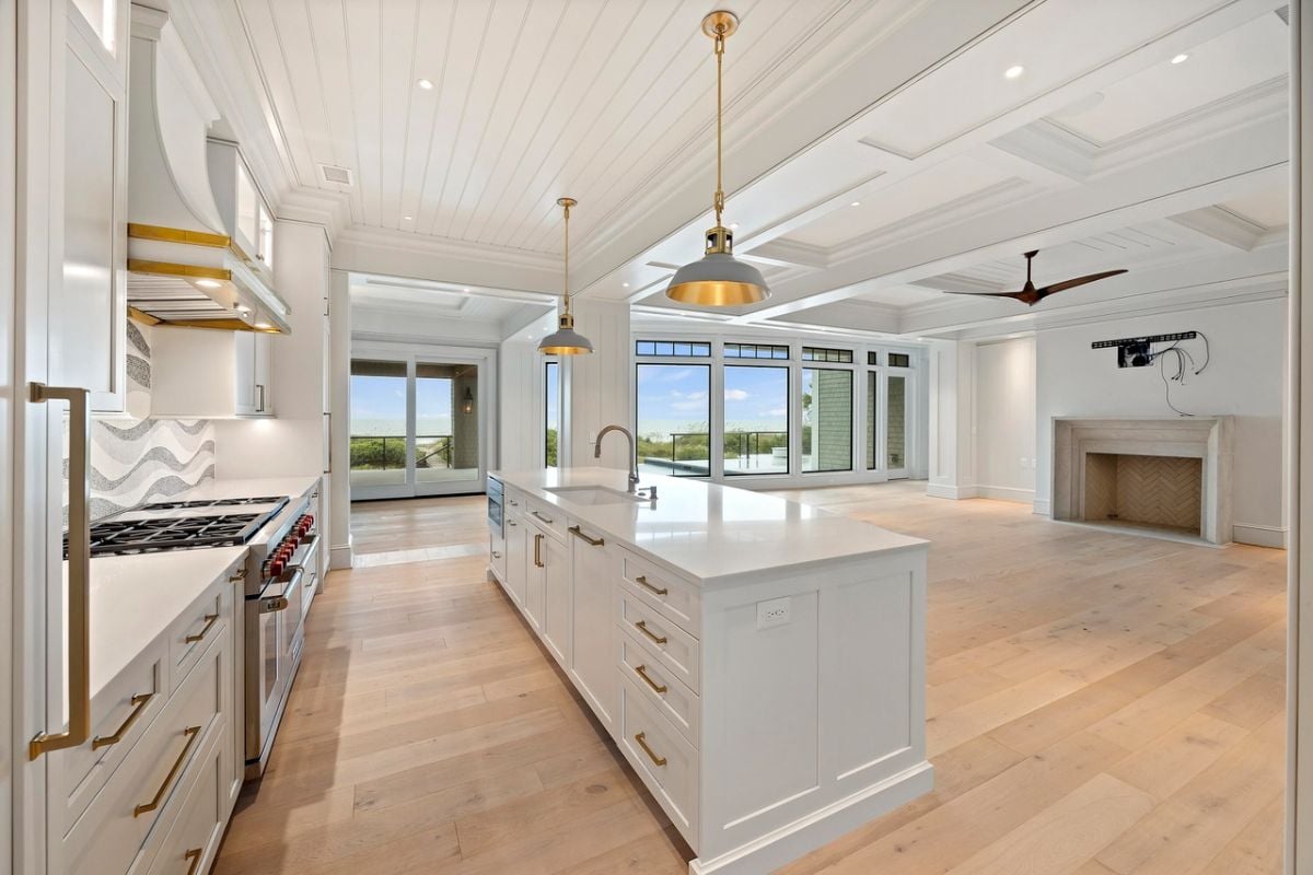 Kitchen with a large island, custom lights, custom cabinets and wood flooring.