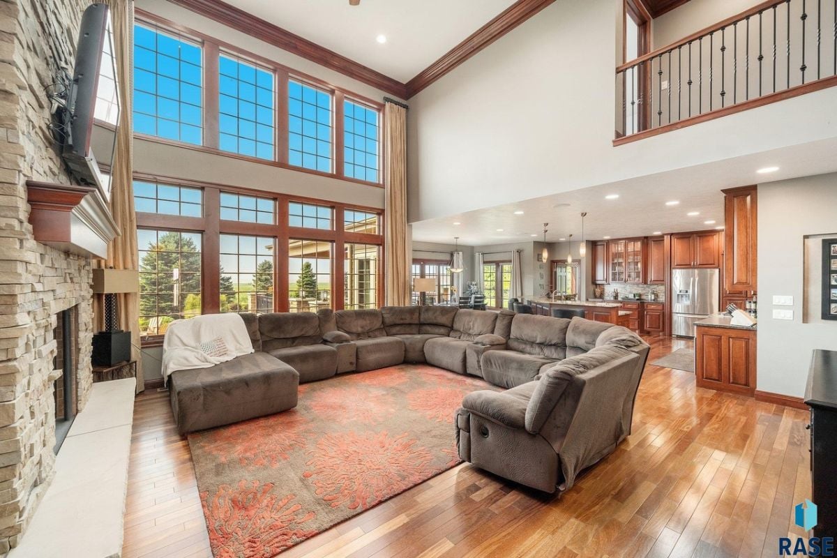 Living room with couches, TV, fireplace and large glass windows.