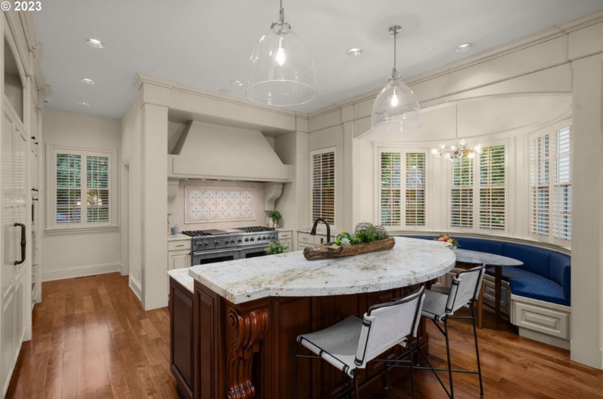 Kitchen with a large island, chandelier, wood flooring, custom lights and a stove.