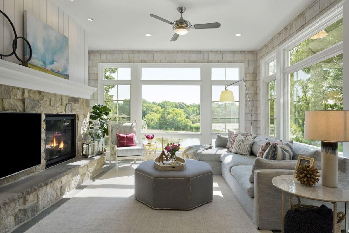 Living room with couches, a TV, glass windows and a fireplace.
