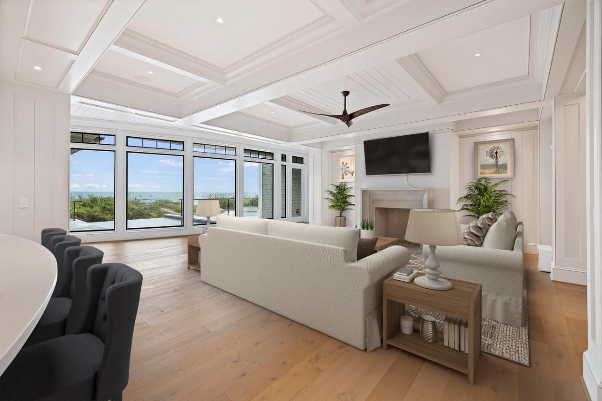 Living room with coffered ceilings, wood flooring, couches, TV, glass walls and a fireplace.