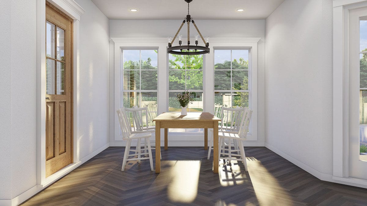 Dining room with a wooden dining set, a round chandelier, and a trio of windows that look out the lush yard.