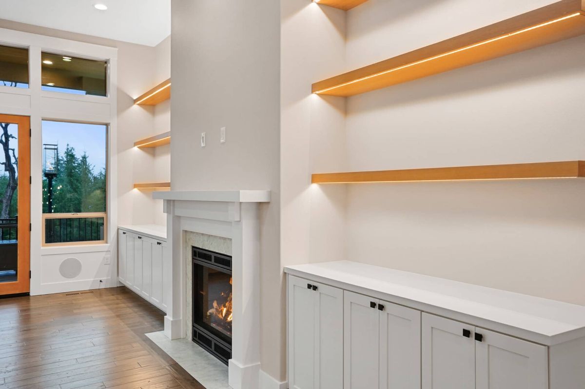 Living room with a fireplace, wooden floors, custom lights and glass doors.
