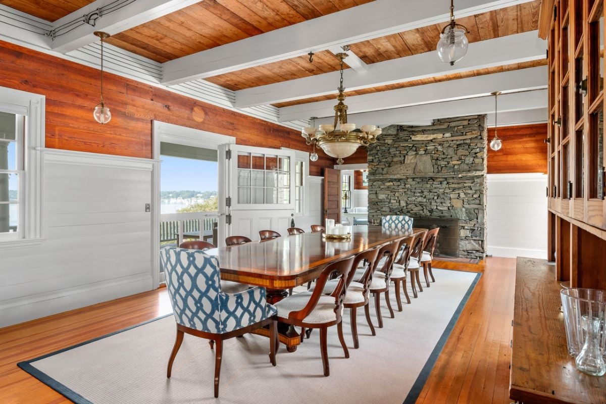 Dining room with a large table, chairs, chandelier, rug and wood flooring.