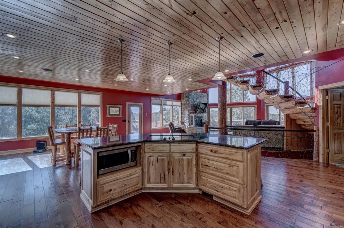 Kitchen with a large island, chandelier, wood flooring, and custom lights.