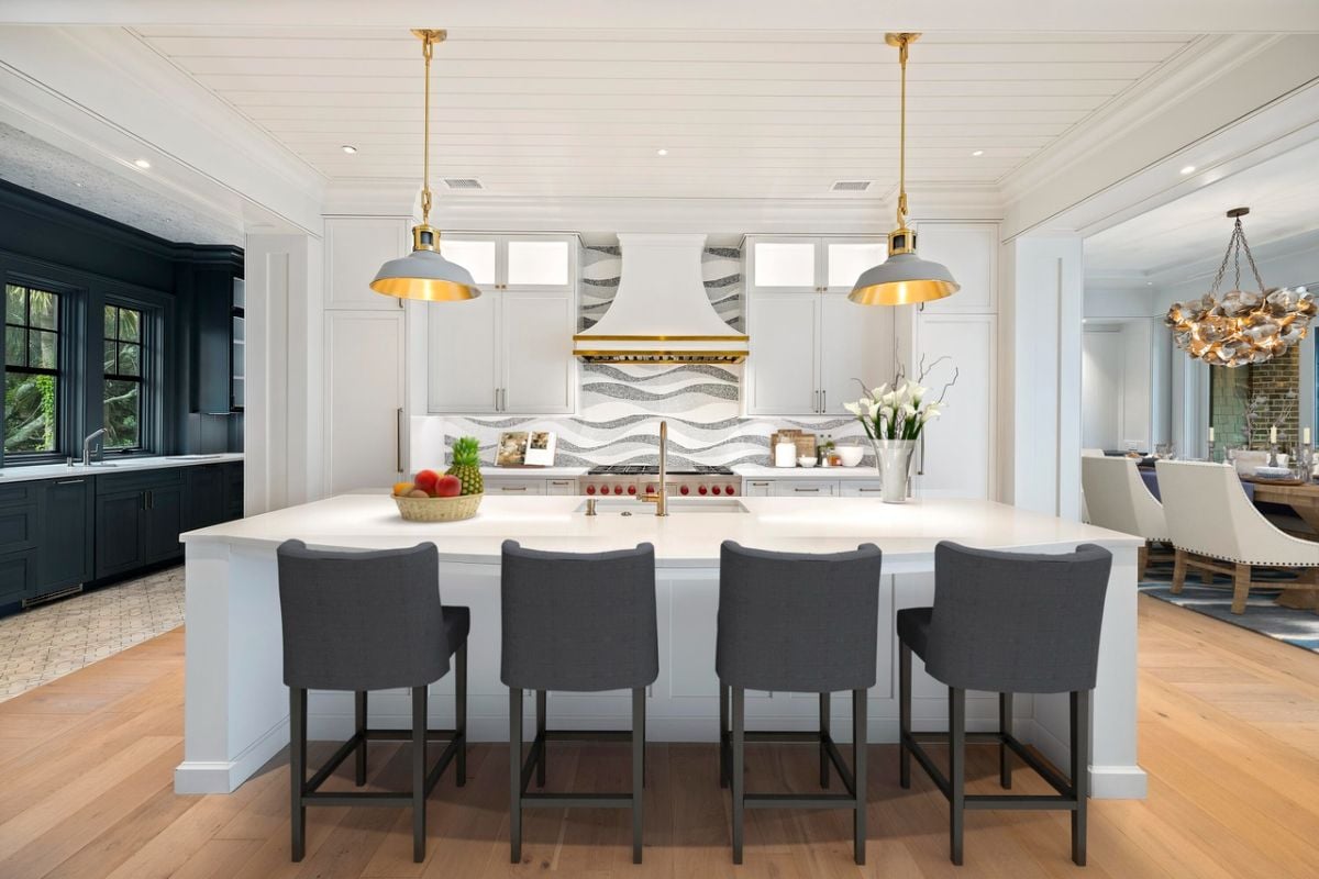 Kitchen with a large island, custom lights, custom cabinets and wood flooring.