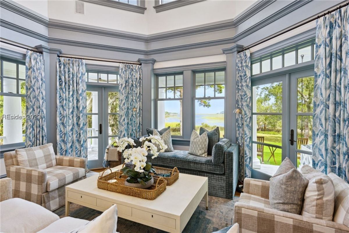 Living room with couches, chandelier and glass windows.