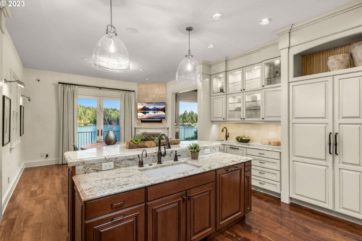 Kitchen with a large island, chandelier, wood flooring, custom lights and custom cabinets.