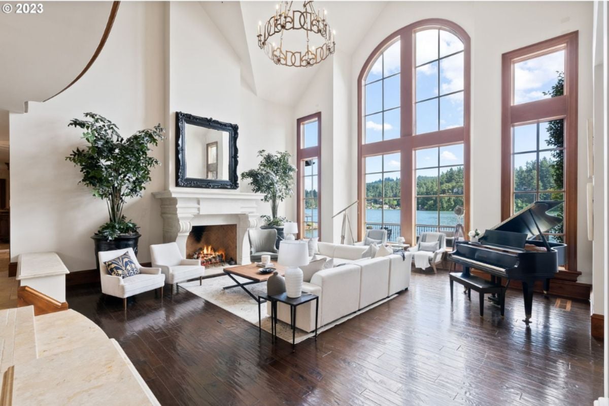 Living room with couches, piano, fireplace and chandelier.
