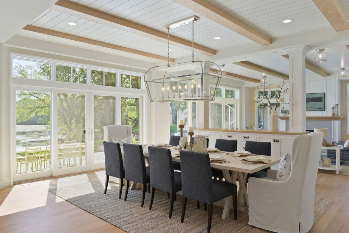Dining room with open beam ceiling, wooden floors, a large table and chairs.
