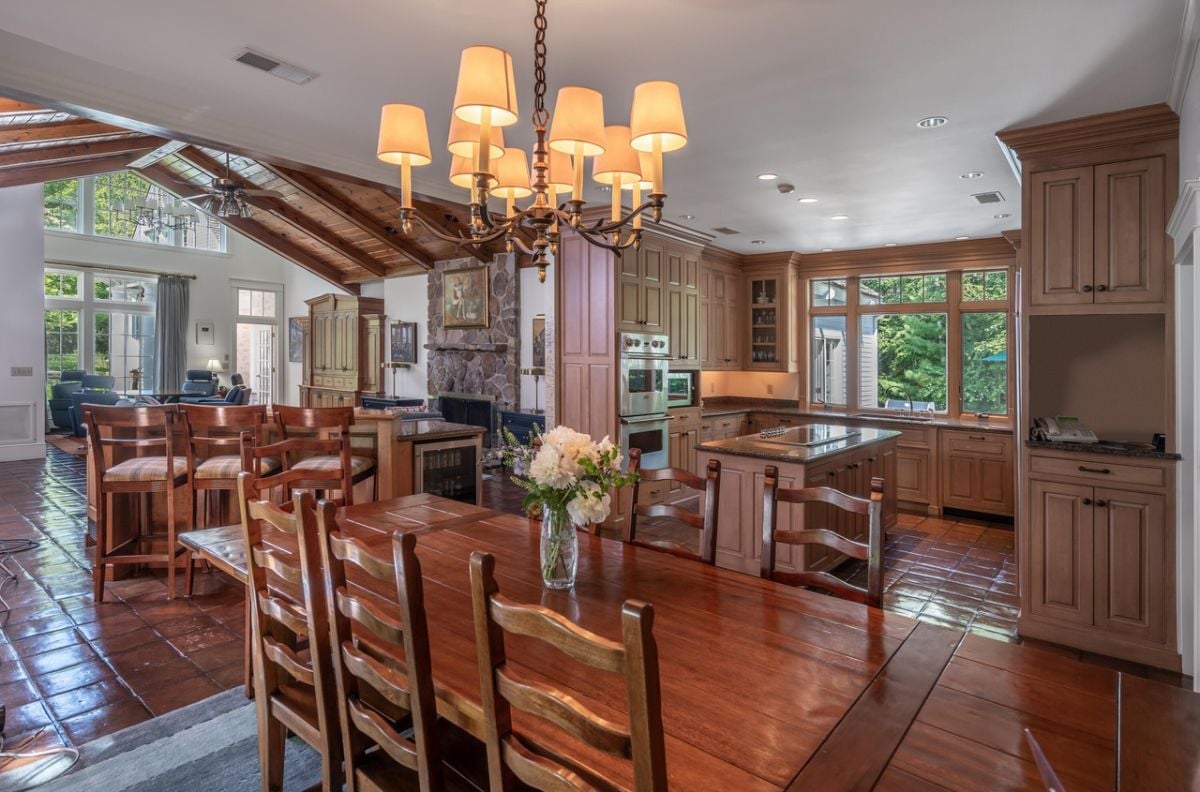 Kitchen with a large island, sink, custom lights, chandelier, dining table and chairs.