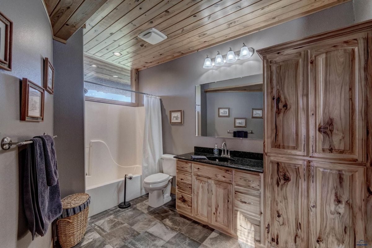 Bathroom with a toilet, sink, mirror, shower and custom lights.