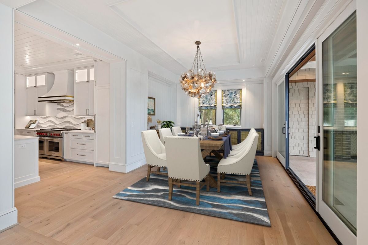 Dining room with a large table, chairs and a chandelier.