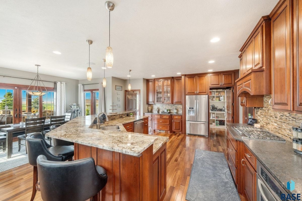 Kitchen with a large center island, wood flooring, custom cabinets and custom lights.