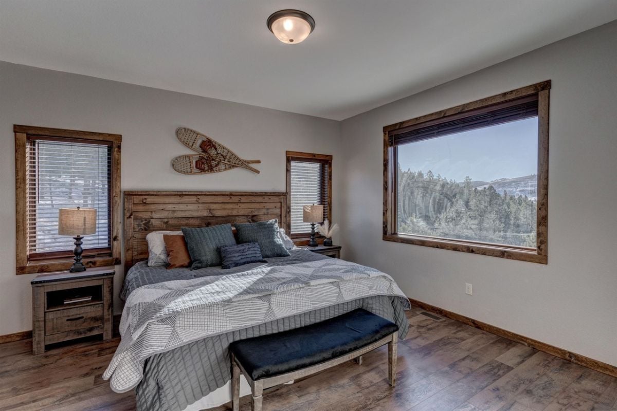 Bedroom with a large bed, wood flooring, and glass windows.