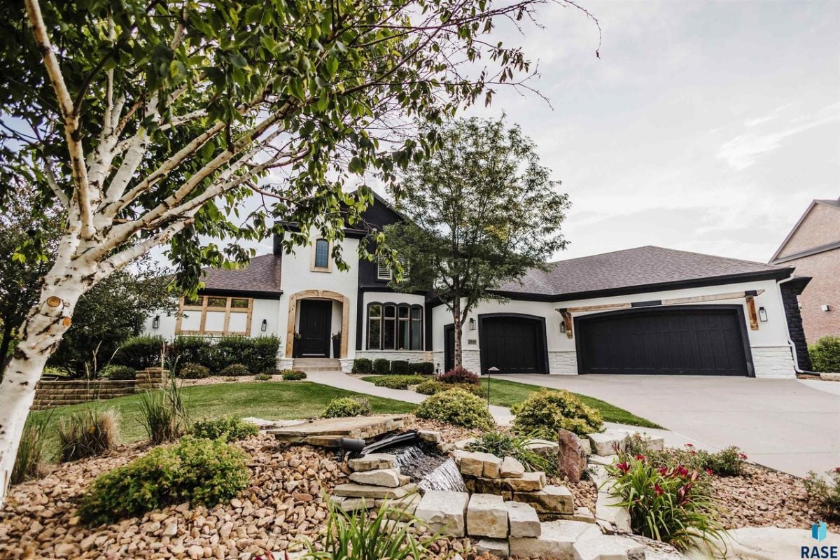 Front view of the house with landscaped lawn, a garage and spacious driveway.