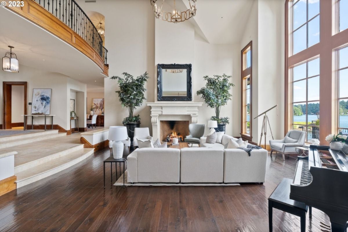Living room with couches, piano, fireplace and chandelier.