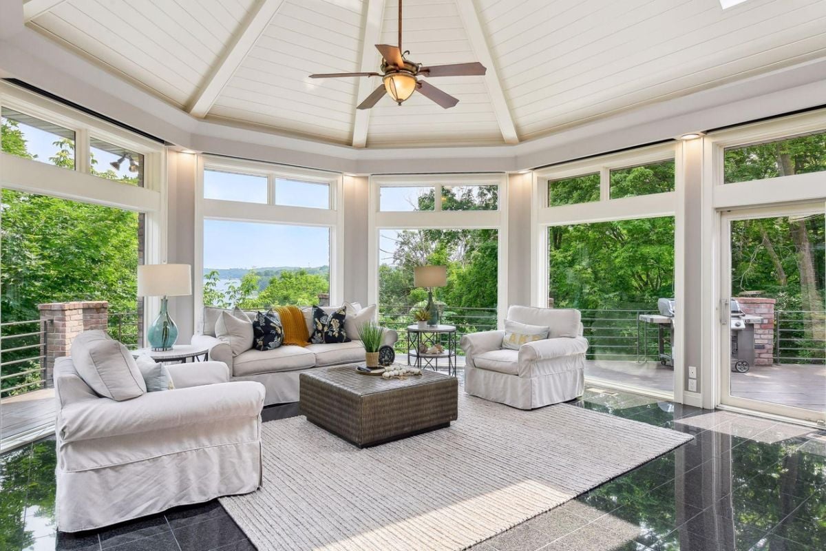 Living room with couches, a ceiling fan and glass wall windows.
