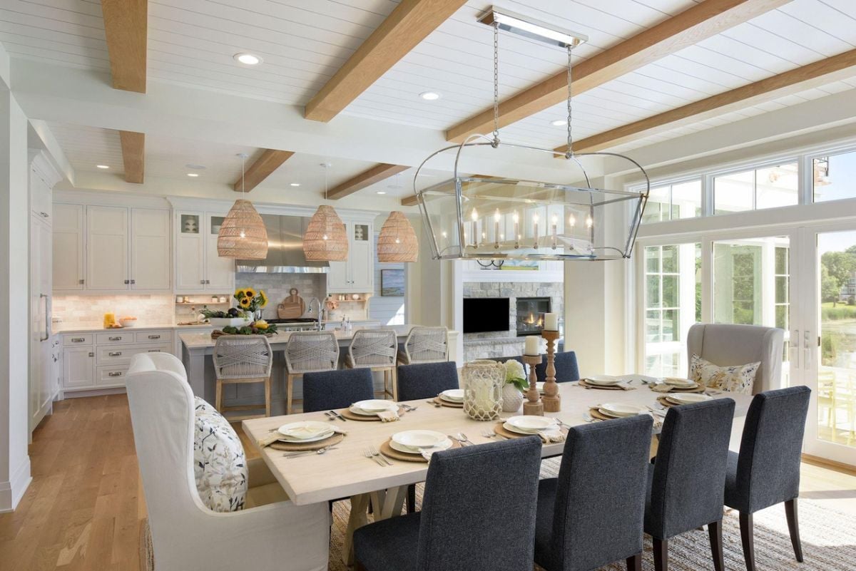 Dining room with open beam ceiling, wooden floors, a large table and chairs.