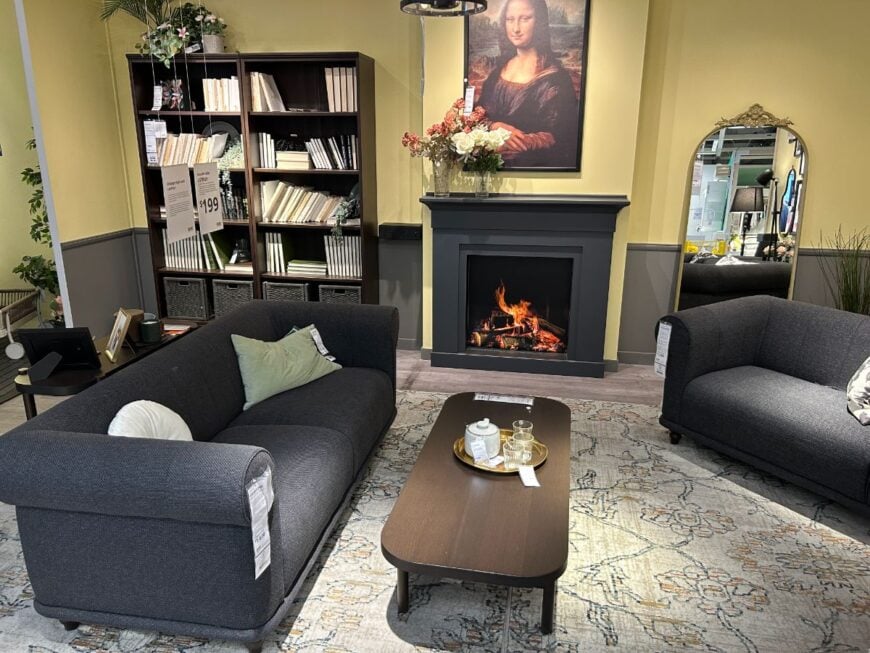 Ikea Showroom features a black sofa, fireplace and a book shelf.