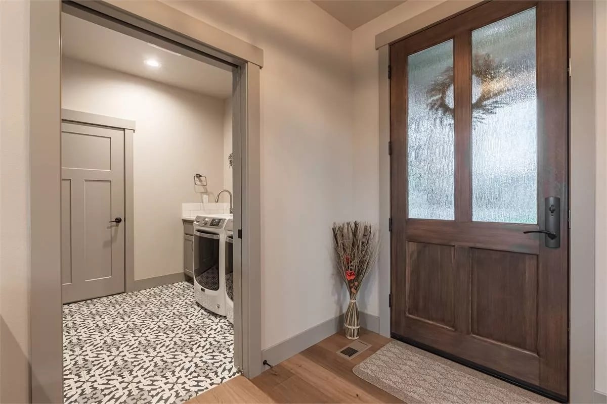 Foyer with a glazed entry door and an opening that leads to the laundry room.