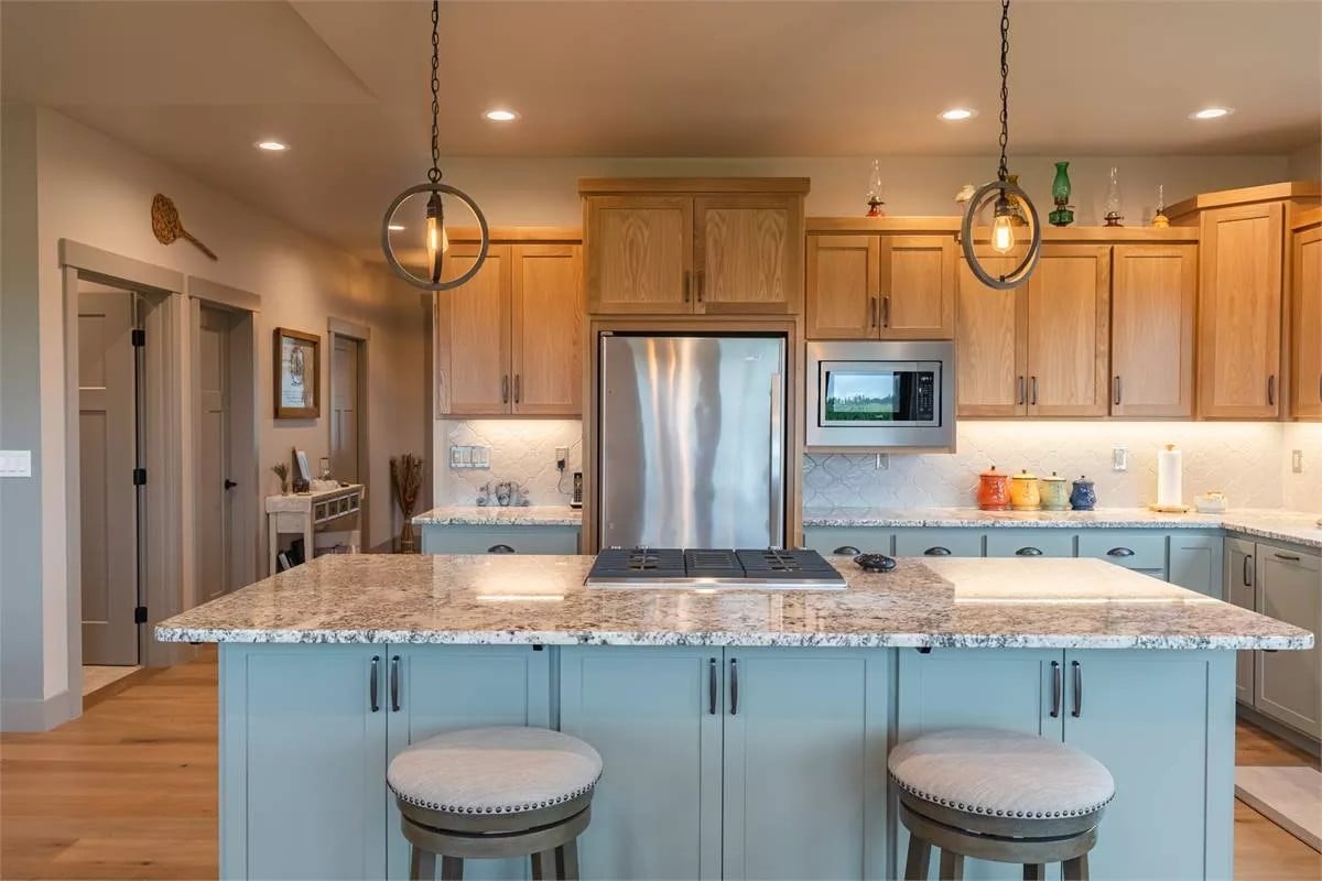 Kitchen with gray and wooden cabinets, stainless steel appliances, and a cooktop island with bar seating.