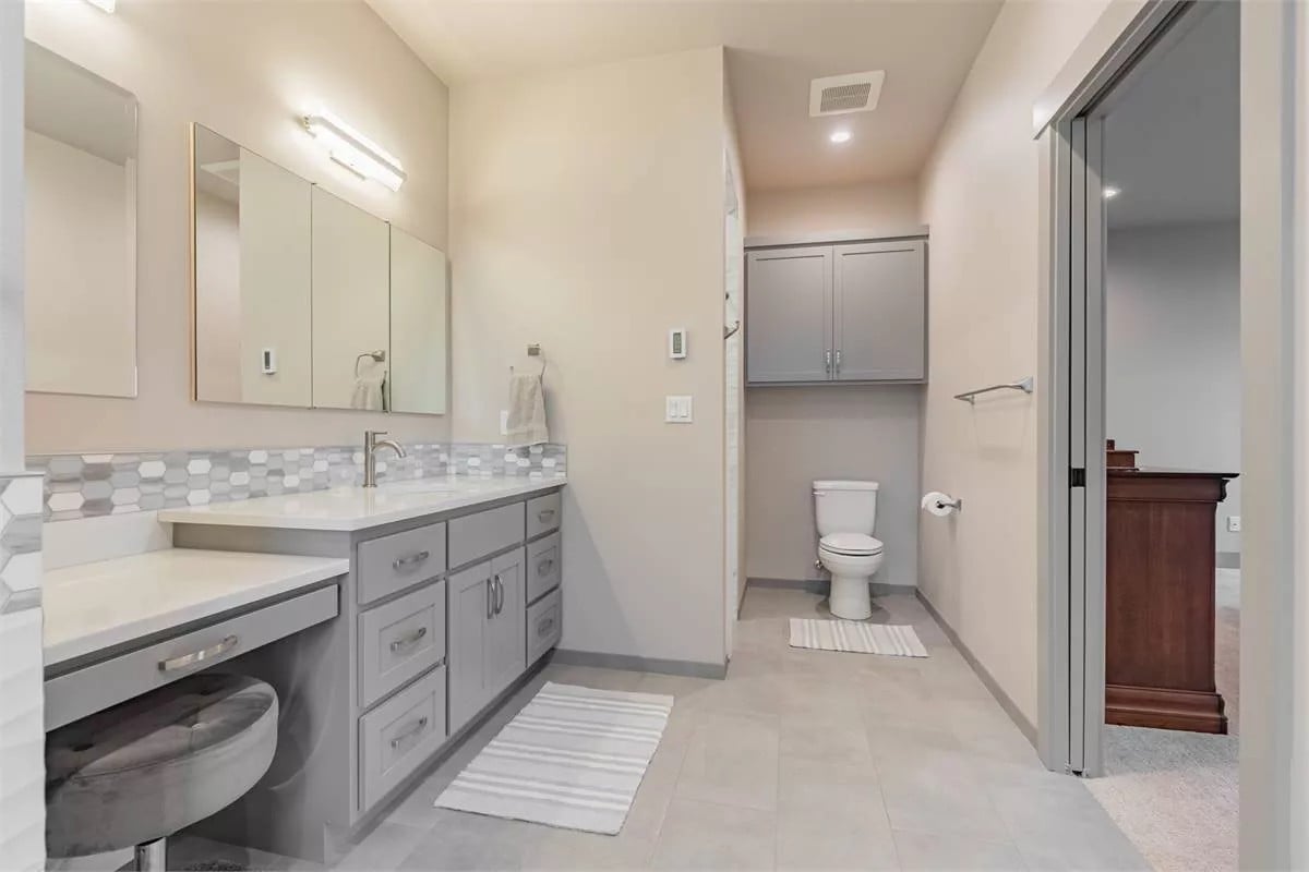 Primary bathroom with a toilet area and an elongated vanity integrated with a makeup counter.