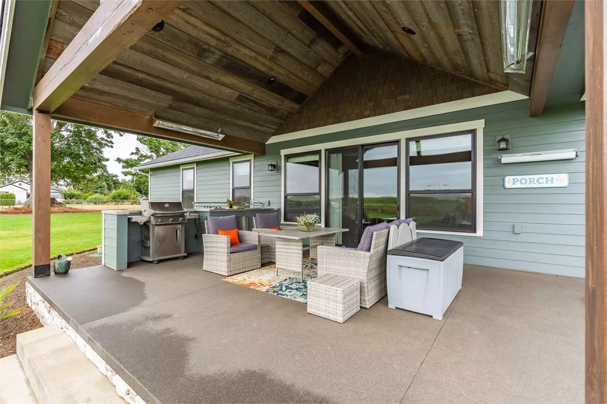 Rear patio with a summer kitchen, wicker seats, and a cathedral ceiling clad in wood planks.