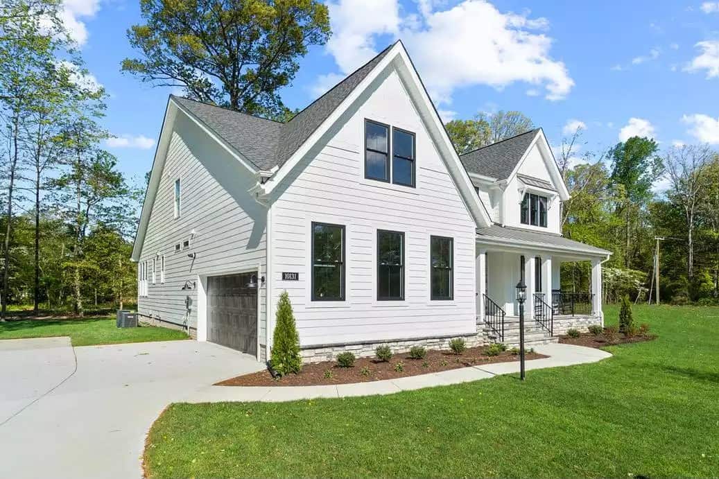 Front-left view showcasing the double side-loading garage with concrete driveway.