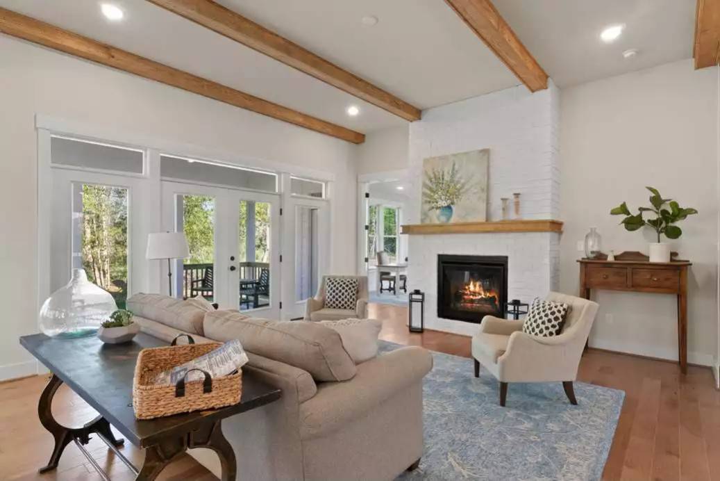 Great room with a gray sofa, wingback chairs, and a fireplace adorned with a painting.