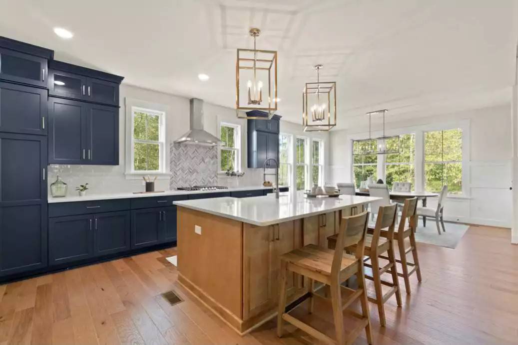 Kitchen with blue cabinetry, marble countertops, and a breakfast island topped with chrome pendants.