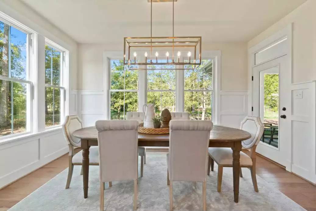Dining room with an oval dining set, a linear chandelier, and stunning backyard views.