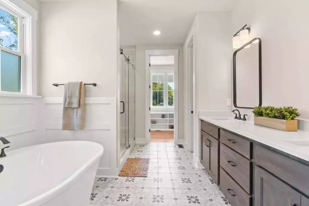 Primary bathroom with a dual sink vanity, a walk-in shower, and a soaking tub over a decorative tiled flooring.