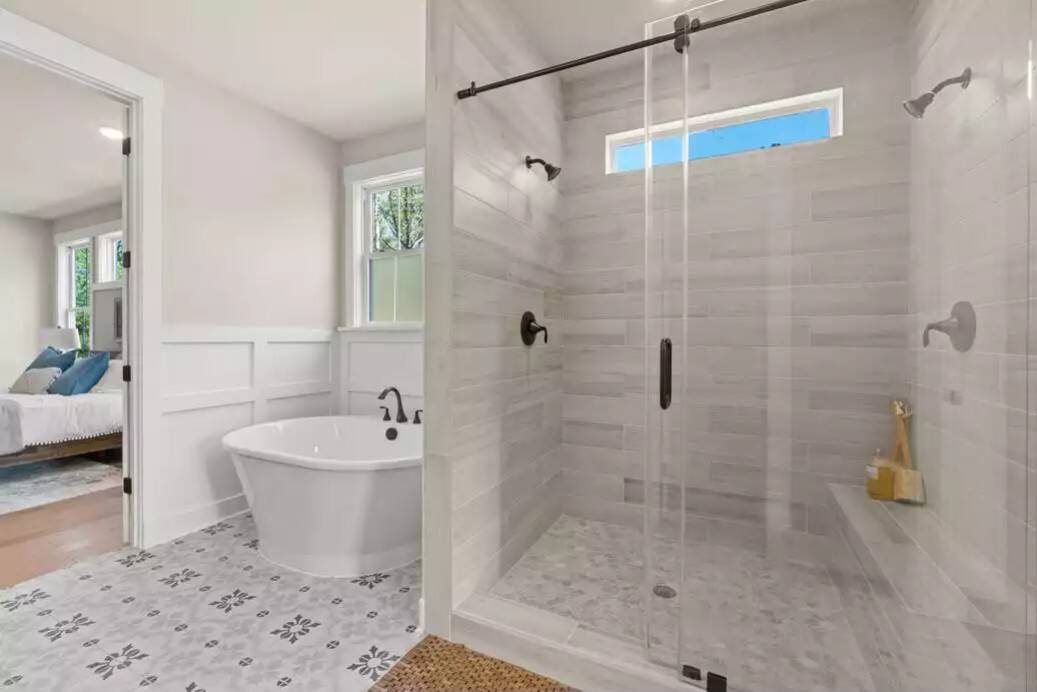 Windows above the bathtub and inside the walk-in shower fill the primary bathroom with natural light.