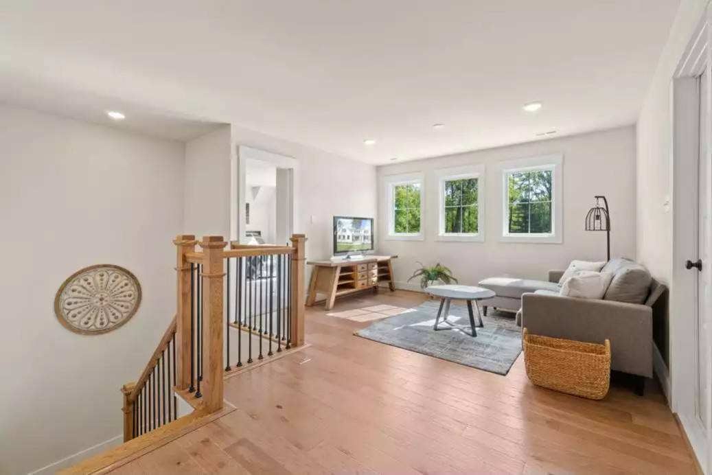 Loft with an L-shaped sofa and a TV sitting on a wooden console table.