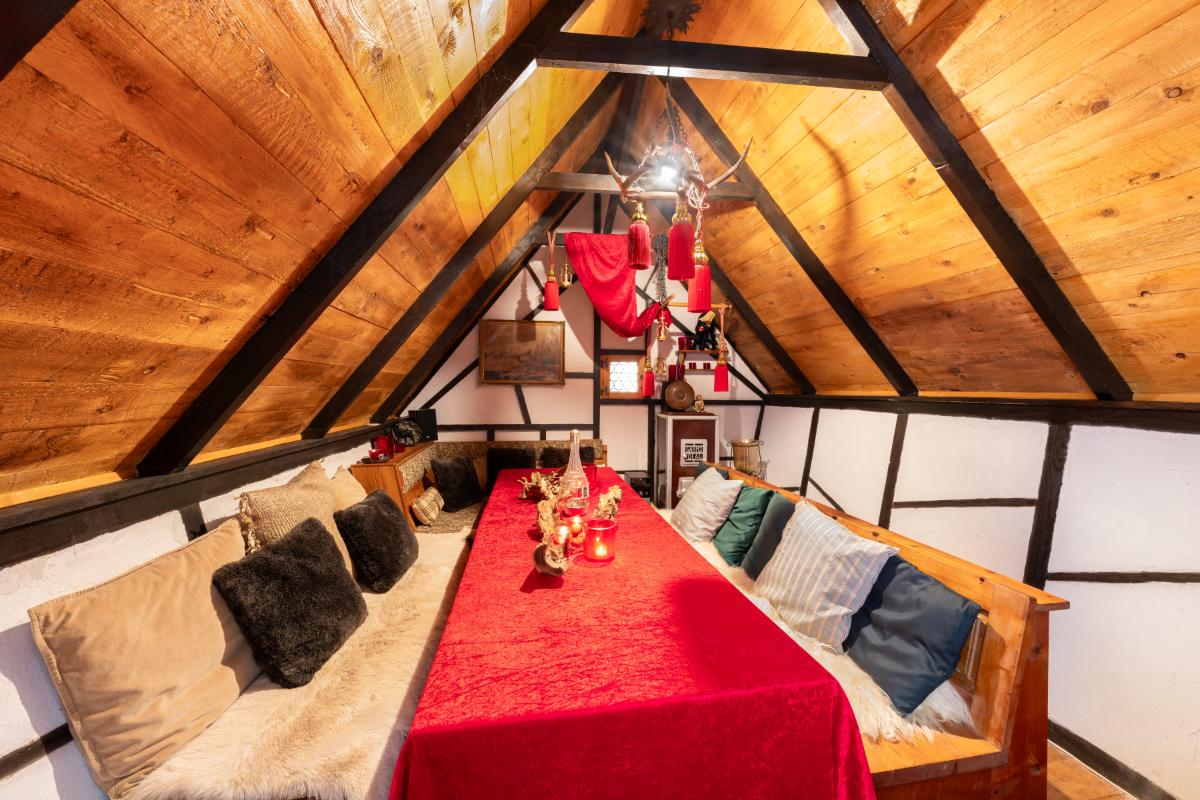 Loft with a large table, bench chairs, and a wooden ceiling.