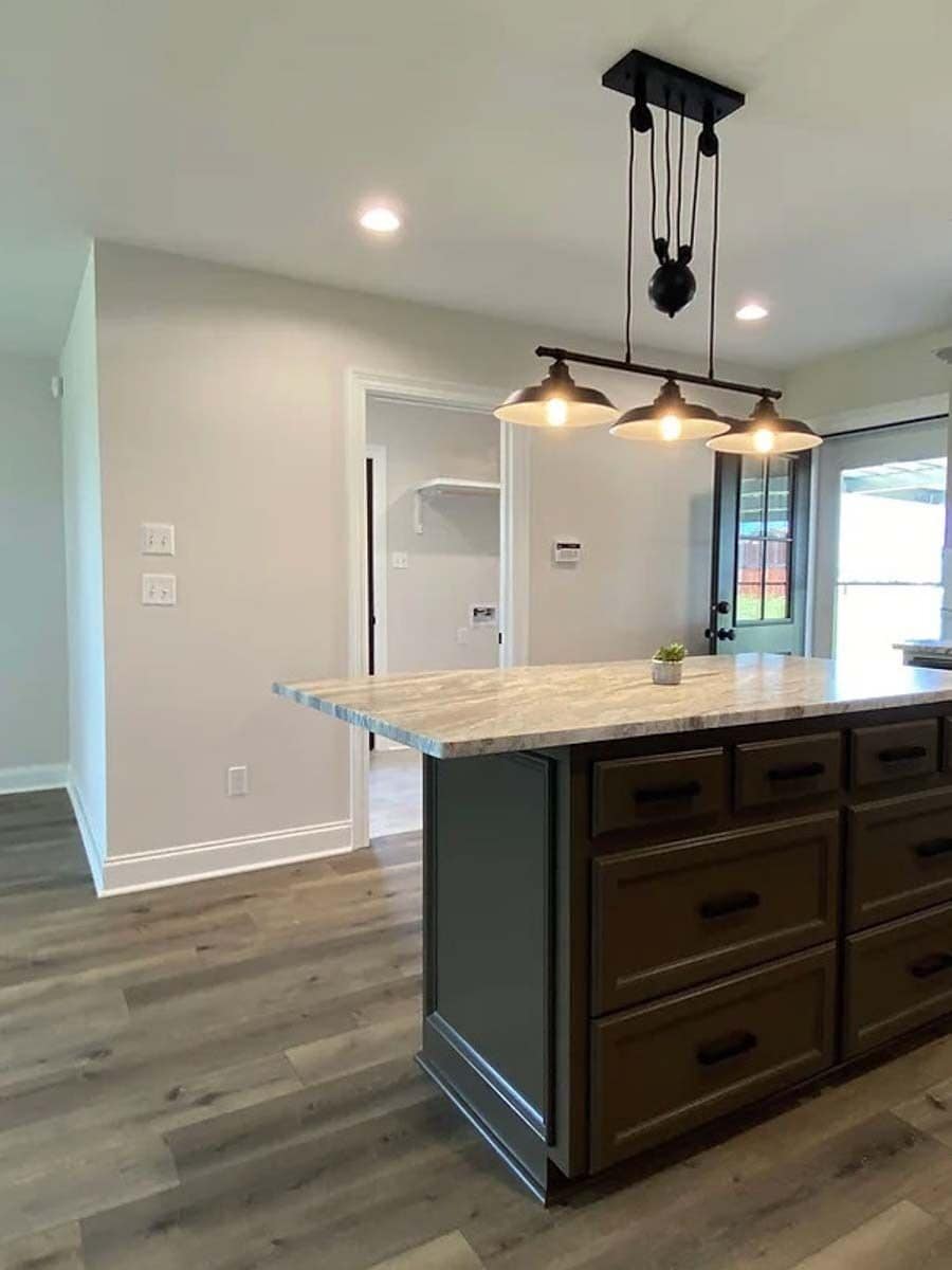 Kitchen island illuminated by warm pendants.