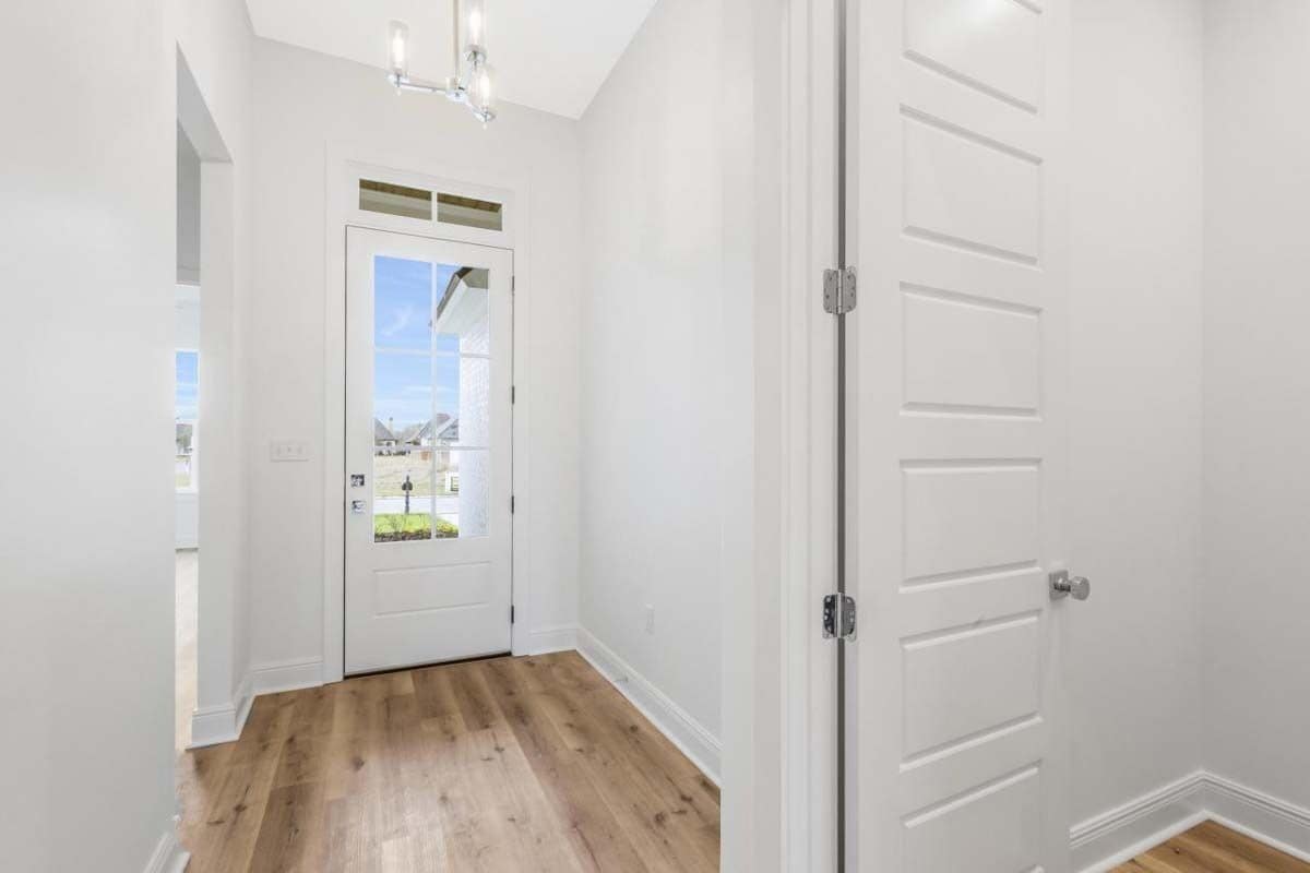 Foyer with a glazed front door and hardwood flooring.
