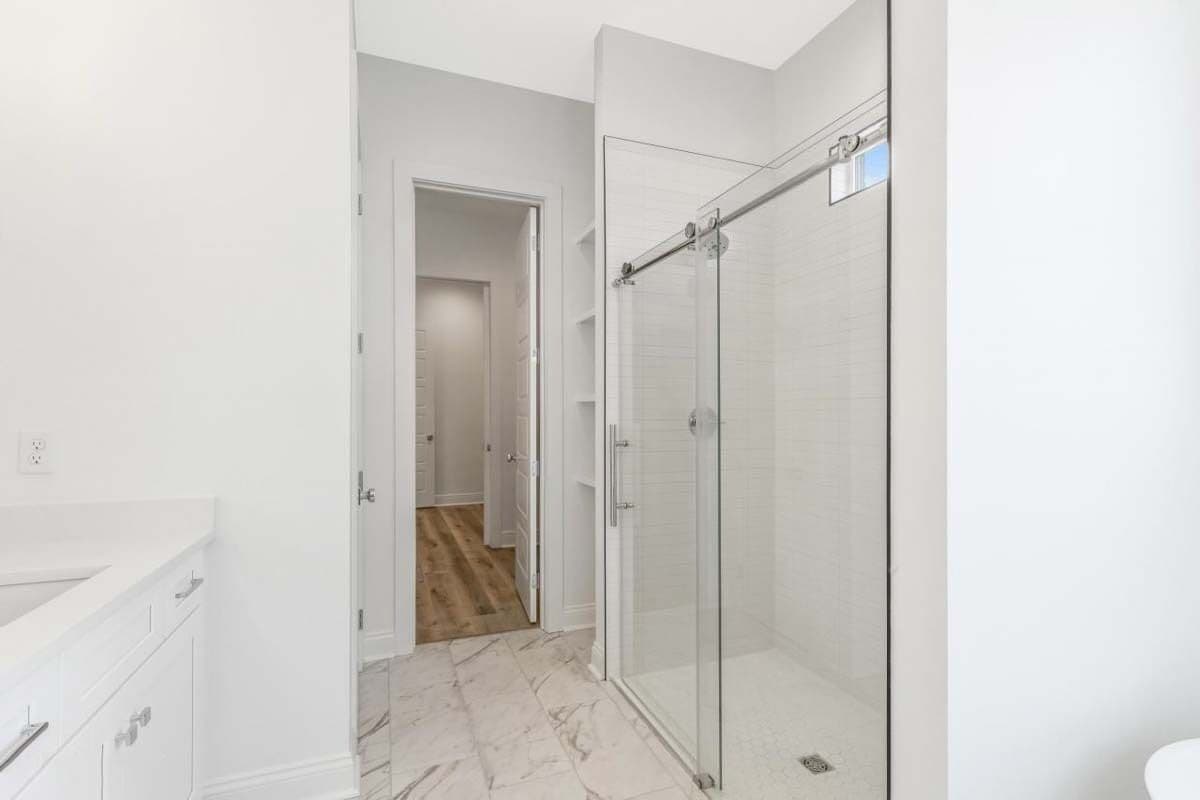 Primary bathroom with a tiled shower and a walk-in closet.