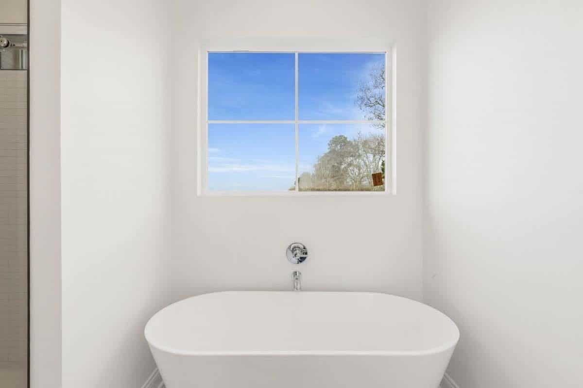 The primary bathroom includes a soaking tub under a white-framed window.