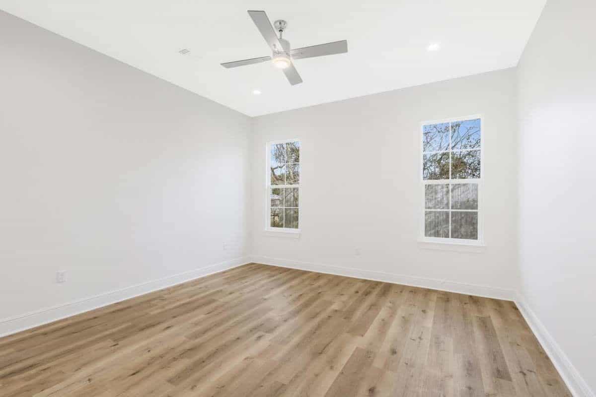 Primary bedroom with white-framed windows and a hardwood floor.