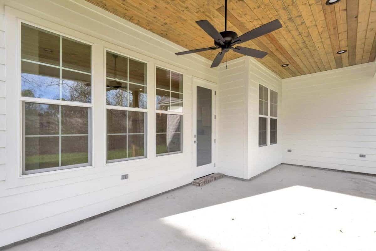Covered porch with a glazed door and a wood-paneled ceiling mounted with a fan.