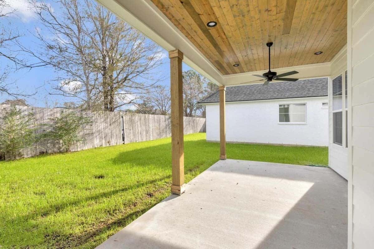 The covered porch seamlessly transitions to a lush green lawn.
